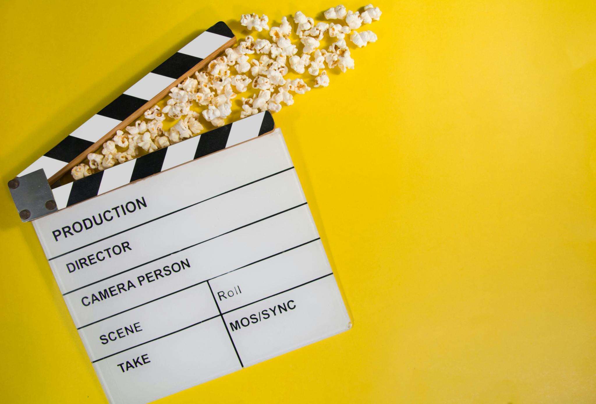 gelber Hintergrund, eine Filmklappe mit Popcorn