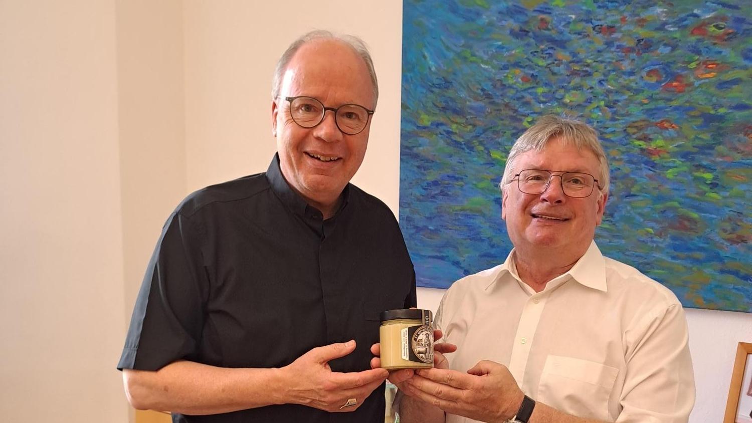 Herr Dekan Leist überreicht Herrn Bischof Ackermann ein Glas Honig