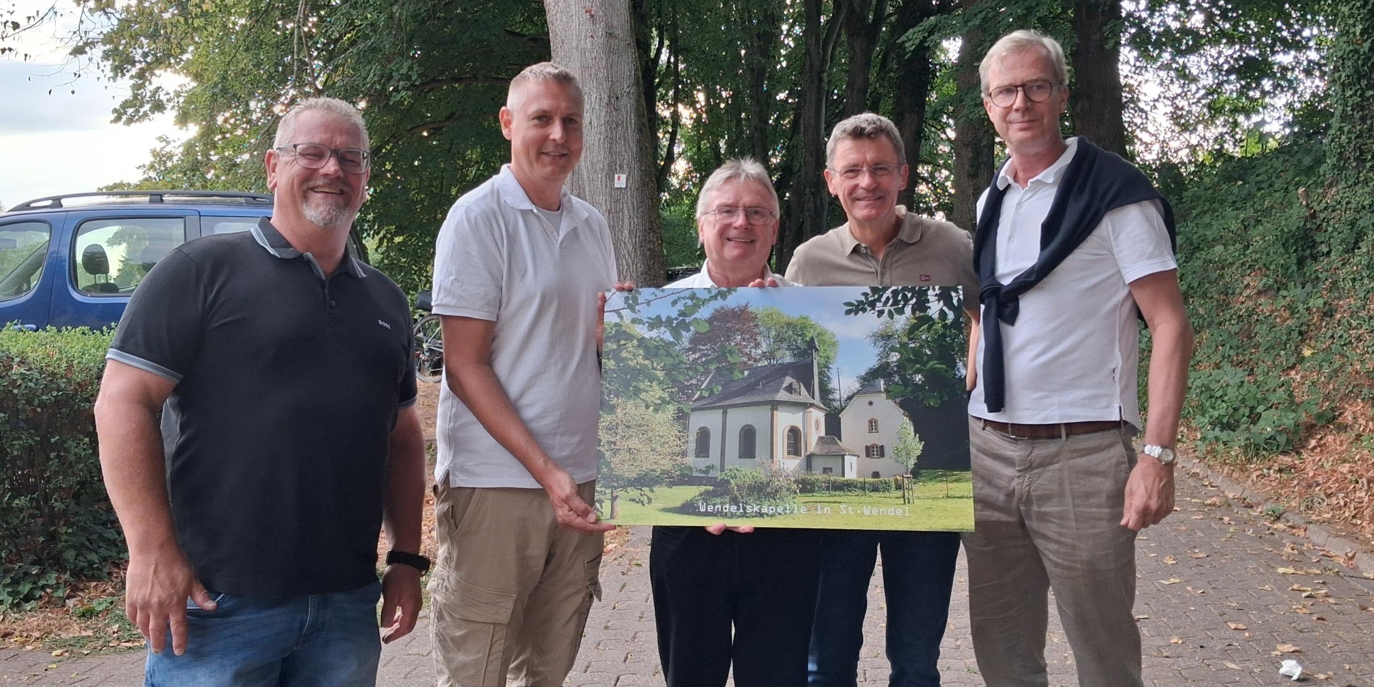 Bürgermeister und Ortsvorsteher überreichen Pastor ein Bild der Wendelskapelle (c) Frau Viktoria Pabian Bürgermeister und Ortsvorsteher überreichen Pastor ein Bild der Wendelskapelle